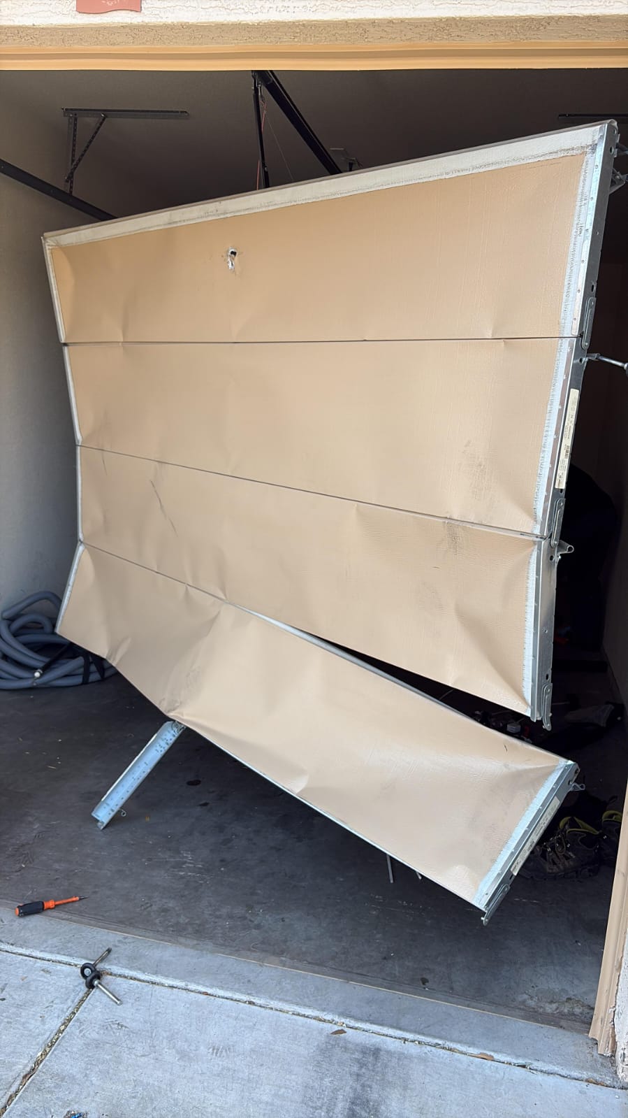 A buckled, badly damaged garage door removed from a Goodyear, AZ home before replacement.